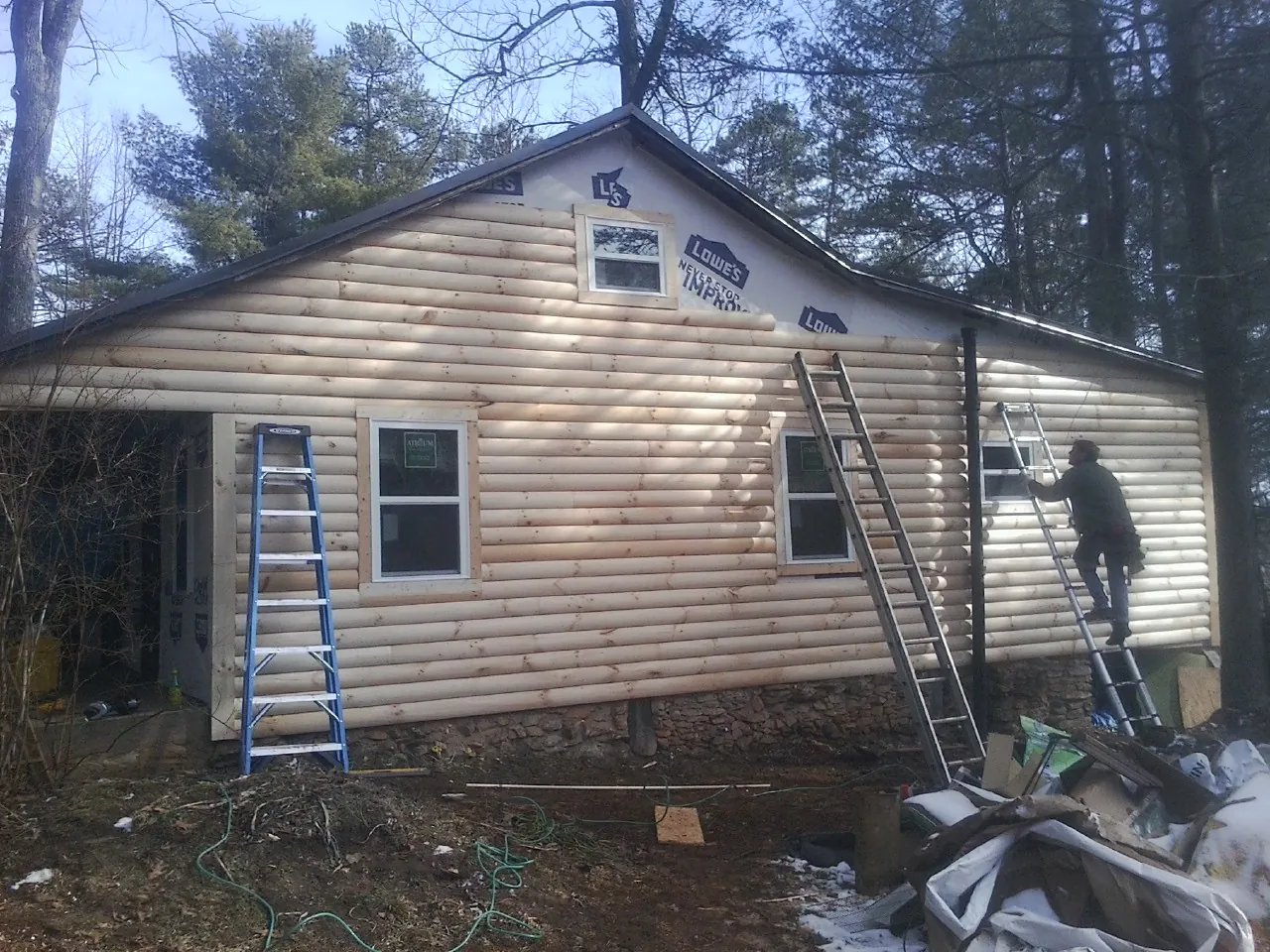 Ladders set against fresh log siding during an exterior remodel in Milldale
