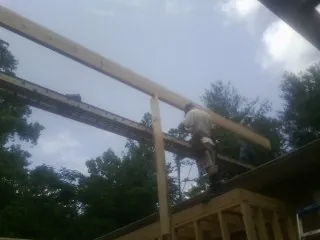 Carpenter setting a ridge beam over a new addition frame — Ice Dam Removal by Roofing Brothers in Milldale