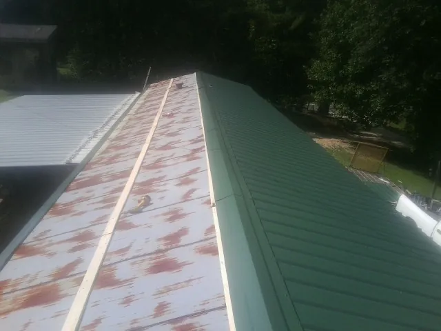 Old rusted panels beside newly installed green metal roofing — Wind Damage Roof Repair by Roofing Brothers in Milldale