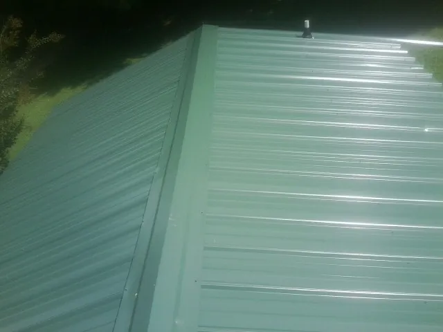 New green metal panels meeting at the ridge of a roof — Flat Roof Repair work by our crew in Milldale