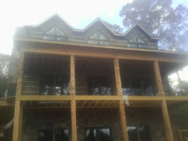 Dormers and porch framing on a large log home under construction — Roof Coating work by our crew in Milldale