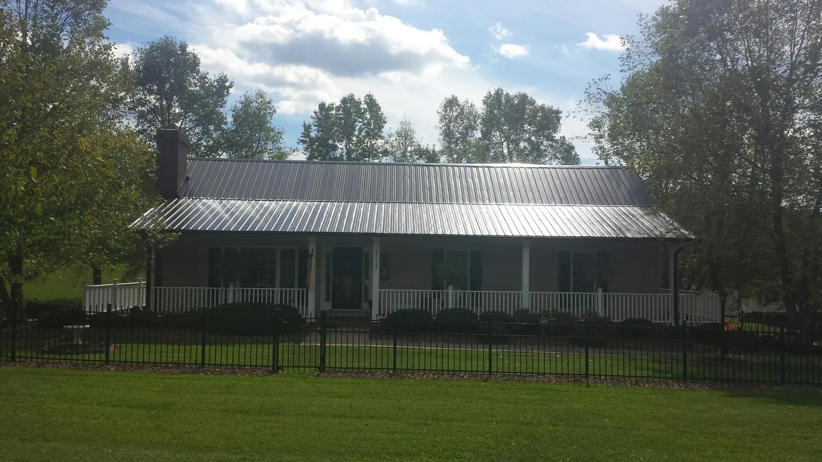 Gray metal roof on a brick ranch with a full width front porch — Gutter Guard Installation work by our crew in Milldale