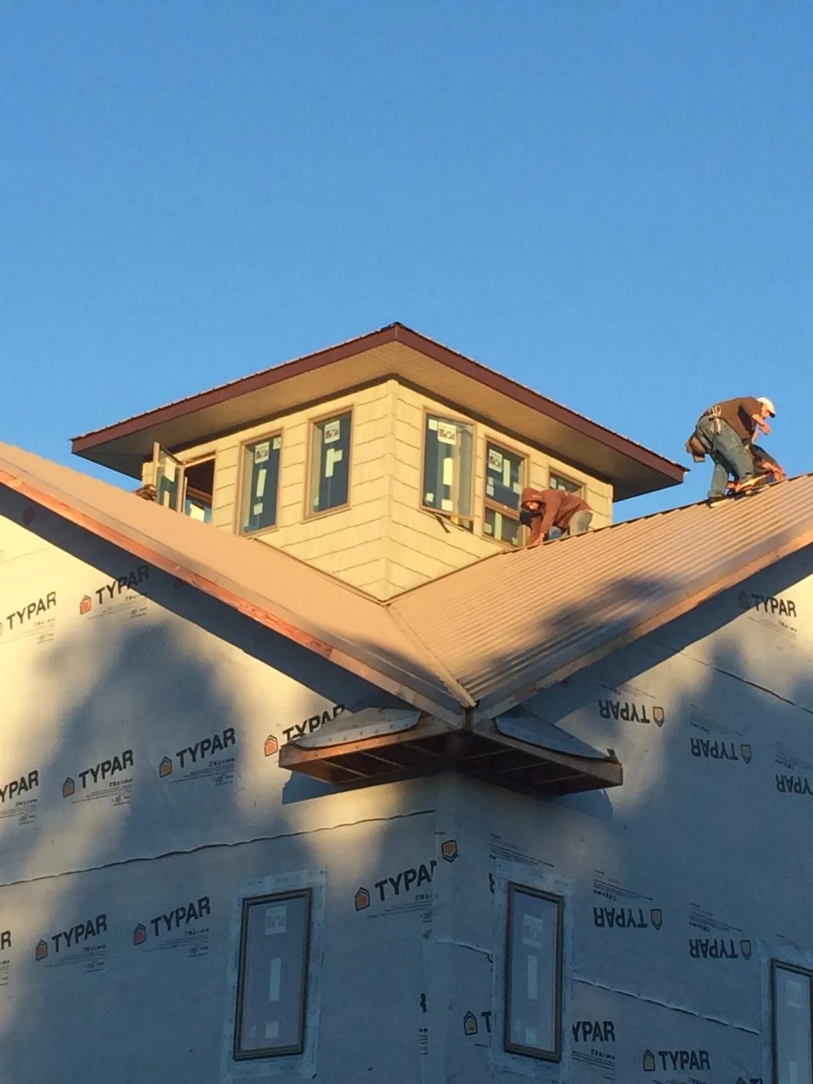 Roofers working around a rooftop cupola on a new metal roof at sunset — Roof Waterproofing in Milldale by Roofing Brothers